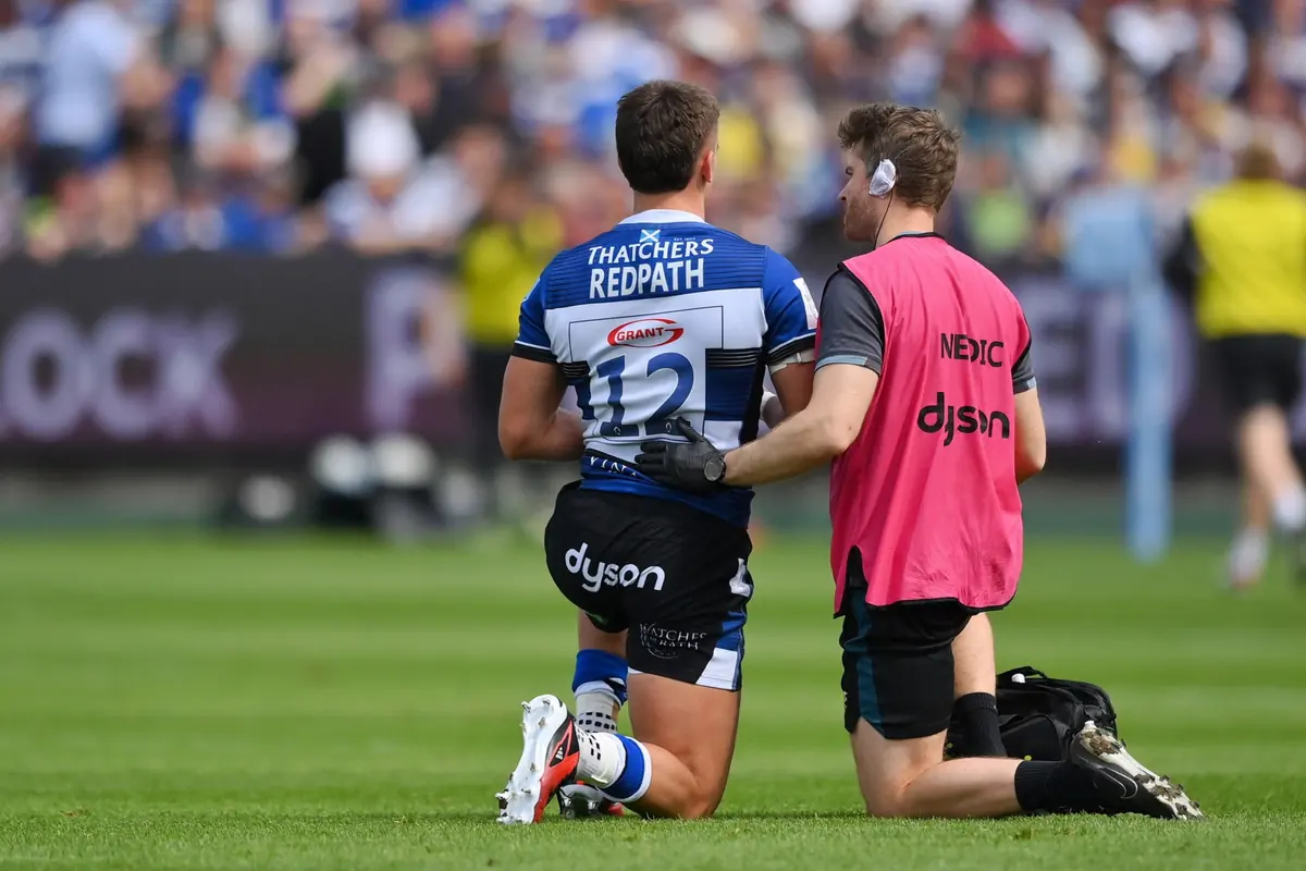 George Gauntlett assisting an injured Bath Rugby player during a match